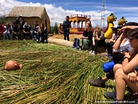 Group tour of a floating reed island, guide is explaining about the history, Puno.