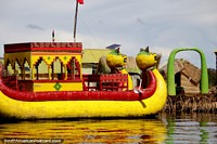 Yellow and red dragon boat glows in the sun as we arrive at another floating island in Puno. Peru, South America.