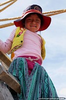 Girl looks down from a ladder, the Uros people of the floating islands in Puno.