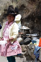 Indigenous woman with a tall hat cooks outside in the mountains in Caraz. Peru, South America.