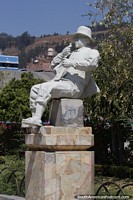 Man sitting eating, white cultural statue at the park in Huaraz. Peru, South America.