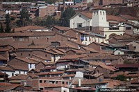 Versão maior do Igreja amarela com telhado de telhas vermelhas na colina com vista para Cusco.