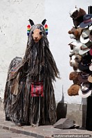 Llama peluda afuera de una tienda de sombreros y moda en Cusco.