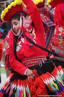 Mujer con sombrero rojo con flores amarillas y vestido multicolor, bailando en Cusco. Perú, Sudamerica.