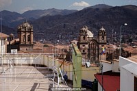 Towers of churches come out from the Plaza de Armas in Cusco, surrounding mountains.
