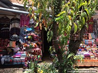 Roupas de lã e xales à venda em um ambiente verde em Cusco.