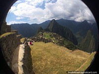Mulher indígena em rosa senta-se com vista para Machu Picchu. Peru, América do Sul.