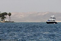 The coast in Paracas with palms and distant mountains, boat moored. Peru, South America.