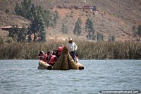 Grupo de pessoas viaja ao redor da lagoa em um barco de plataforma de palha feito de junco em Namora. Peru, América do Sul.