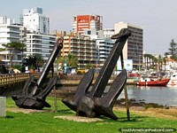 Um par de enormes monumentos da âncora pretos na grama ao longo da calçadão no porto em Punta do Este. Uruguai, América do Sul.