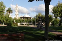 Plaza Constitucion, stone monument, kiosk and church tower, Fray Bentos. Uruguay, South America.