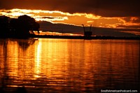 O céu torna-se cor-de-laranja-escuro como o ocaso desenha a um fim na Fray Bentos. Uruguai, América do Sul.