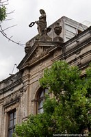 Antigua fachada de piedra con una estatua femenina en la parte superior y una ventana arqueada en Paysandú. Uruguay, Sudamerica.