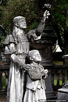 Mulher e criança, apoia flores, monumento de pedra no cemitério velho em Paysandu. Uruguai, América do Sul.