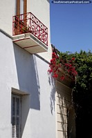 Red iron balcony, a white facade and red flowers, the streets in Colonia. Uruguay, South America.