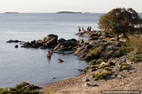 View of the river and people on the rocks in the afternoon around Santa Rita Bastion in Colonia. Uruguay, South America.