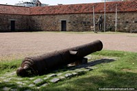 Larger version of Cannon at the plaza of the Dragons Barracks, stone buildings and statue, Maldonado.