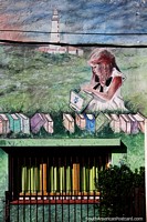 A criança senta-se na grama com livros e um farol distante, mural em Punta do Este. Uruguai, América do Sul.