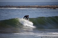 Surfer catches a nice wave at Brava Beach, the rough side of the point in Punta del Este. Uruguay, South America.