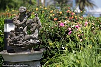 Figuras de ángeles de una fuente de piedra en jardines llenos de flores coloridas en Punta del Este. Uruguay, Sudamerica.