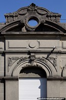 Stone facade with large portholes, flowers and leaves and arched door in Rocha. Uruguay, South America.