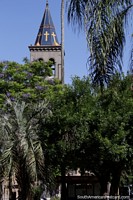 Versión más grande de Campanario azul y dorado de la iglesia y árbol púrpura en la plaza de Tacuarembo.