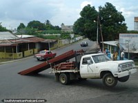 Larger version of A vehicle overloaded with steel bars tips up on the road.