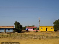Versión más grande de Casas con mucho color pintadas de azul, rosa y amarillo en el campo al oeste de Coro.