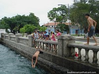 Os habitantes locais de Porto Cabello mergulham-se do pilar de ponte no Dia de Anos Novos 2011. Venezuela, América do Sul.