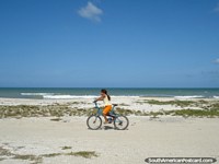 Girl rides a bike along La Restinga beach on Isla Margarita. Venezuela, South America.