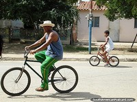 Man and boy ride bicycles in the street in Robledal on Isla Margarita. Venezuela, South America.