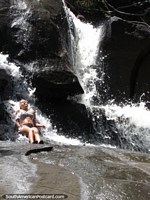 Girl on rocks enjoys the cool waterfall during lunchbreak on the Angel Falls tour. Venezuela, South America.