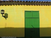 Porta de madeira verde e uma parede amarela com uma iluminação de rua em Coro. Venezuela, América do Sul.
