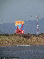 Os pássaros voam para além de uma enorme imagem de quadro de avisos e cartazes do presidente Chavez na praia de La Vela de Coro em Coro. Venezuela, América do Sul.