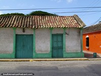 Versão maior do Uma telha cobriu o edifïcio com telhado com portas verdes em Pueblo Nuevo.