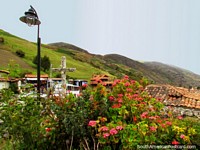 Pink flowers, a stone cross, a lamp, tiled roofs and hills, San Rafael de Mucuchies. Venezuela, South America.