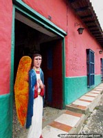 An angel with wings figure stands outside the pink 'Casa del Paramo' in San Isidro de Apartaderos. Venezuela, South America.