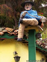 A bearded man with hat and cane figure sits on a roof in La Mucuchache. Venezuela, South America.