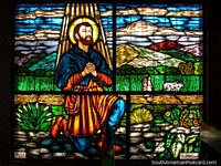 Man kneels down on his farm stained glass window at St. Benedict Chapel in Timotes.