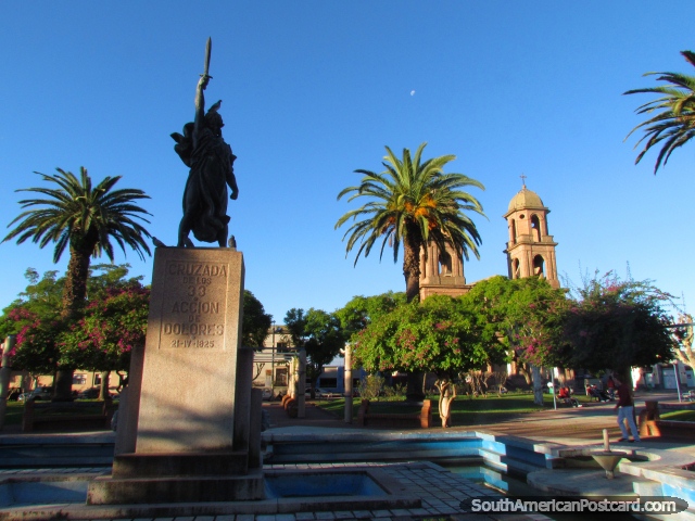 The beautiful Plaza Constitucion in Dolores with monument, cathedral, palms and magneta leaved trees. (640x480px). Uruguay, South America.