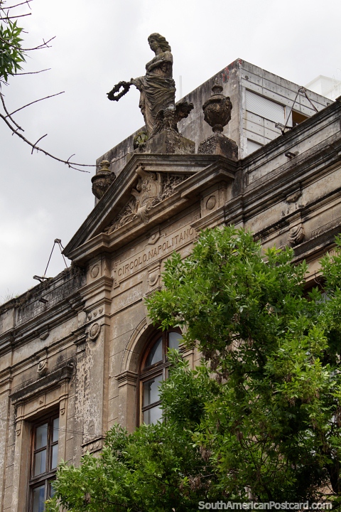 Antigua fachada de piedra con una estatua femenina en la parte superior y una ventana arqueada en Paysandú. (480x720px). Uruguay, Sudamerica.