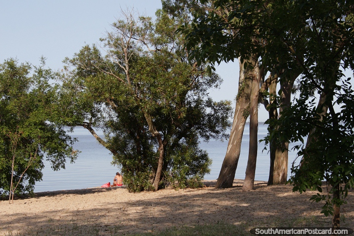 A woman relaxes at the rivers edge at Sere Beach in Carmelo, sunny and shady. (720x480px). Uruguay, South America.