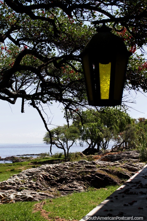 Yellow lantern, rocks and trees, looking out to the river in Colonia. (480x720px). Uruguay, South America.