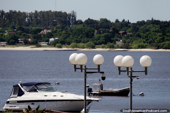Boats and round street lamps, looking across the water to beaches and houses among trees in Colonia. (720x480px). Uruguay, South America.