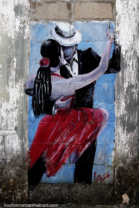 Bailando tango, un hombre en blanco y negro y una mujer con un vestido rojo, pintura callejera en Colonia. (480x720px). Uruguay, Sudamerica.