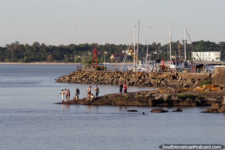 People fishing from the rocks near the port in Colonia del Sacramento. (720x480px). Uruguay, South America.