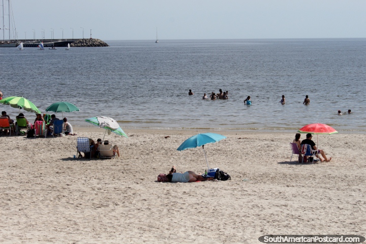 La gente disfruta de la playa y las aguas en Piriápolis mientras la gente navega en la distancia. (720x480px). Uruguay, Sudamerica.