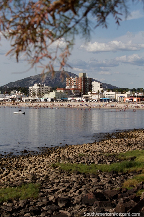 View across the rocks and still waters to the beach, city and mountain in Piriapolis. (480x720px). Uruguay, South America.