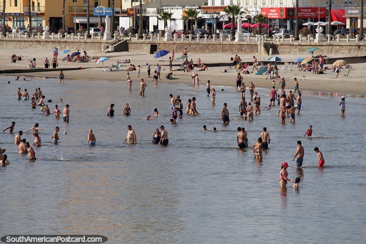 People loving the water in Piriapolis with restaurants, shops and hotels at the back. (720x480px). Uruguay, South America.
