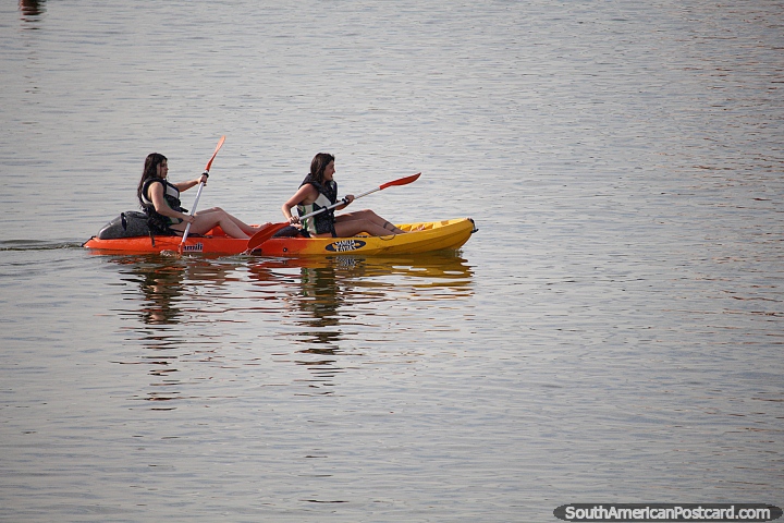 a pair of girls paddle a kayak on the calm waters in Piriapolis, rent from Samoa Kayaks. (720x480px). Uruguay, South America.